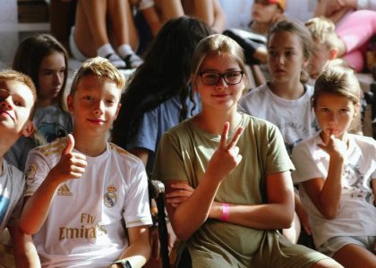 Cheerful group of children sitting together at an indoor event, showcasing friendships and diversity.